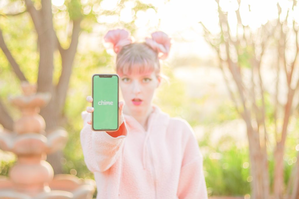 Chime app on phone screen held by woman in a pink shirt