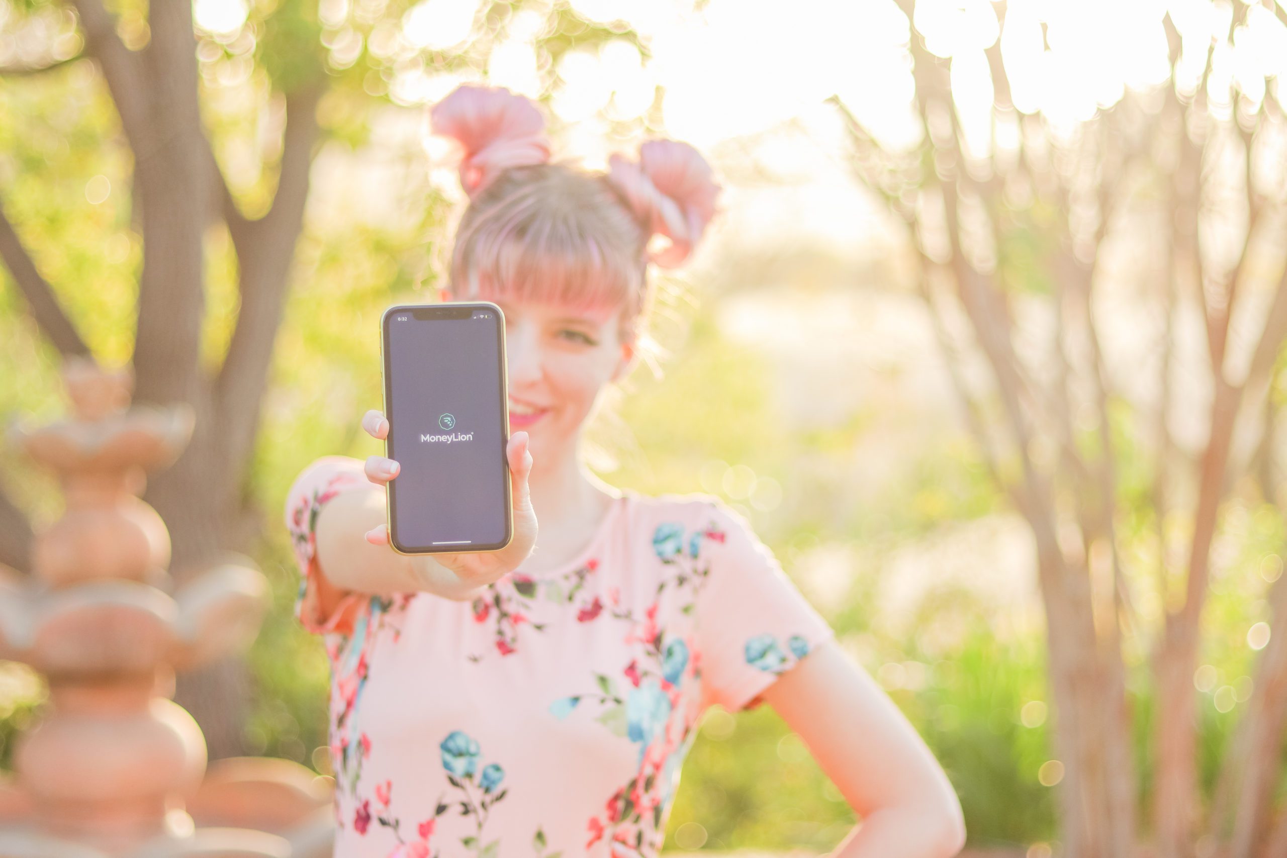 MoneyLion app on phone screen held by woman in backyard