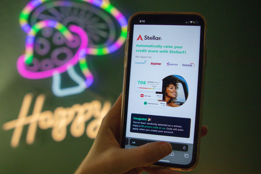 StellarFi website on phone screen describing how the app can help raise your credit score
