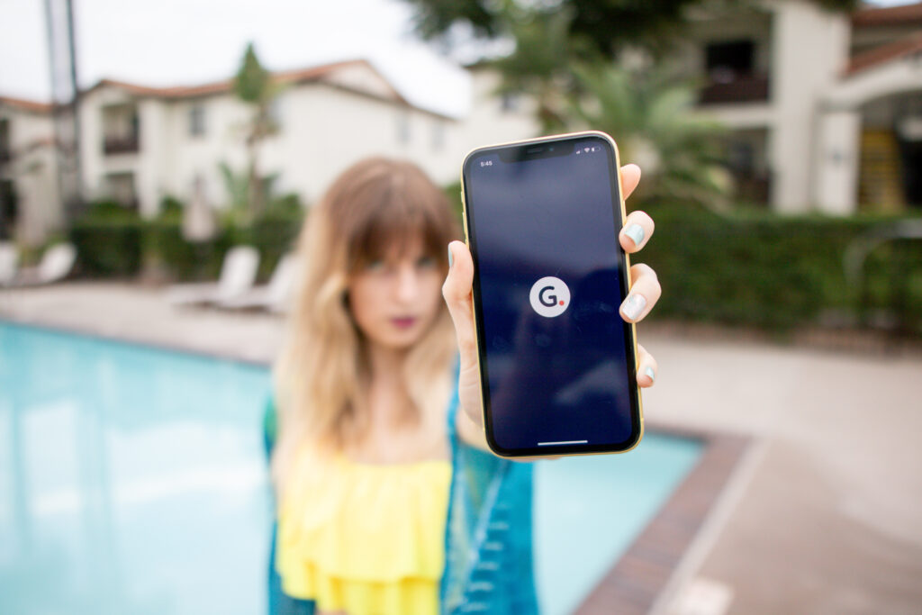 Girl in a yellow top by the pool, showing a phone with the Gerald Wallet App displayed