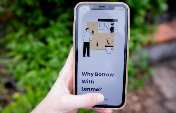 Woman's hand holding a phone advertising Lenme personal loans