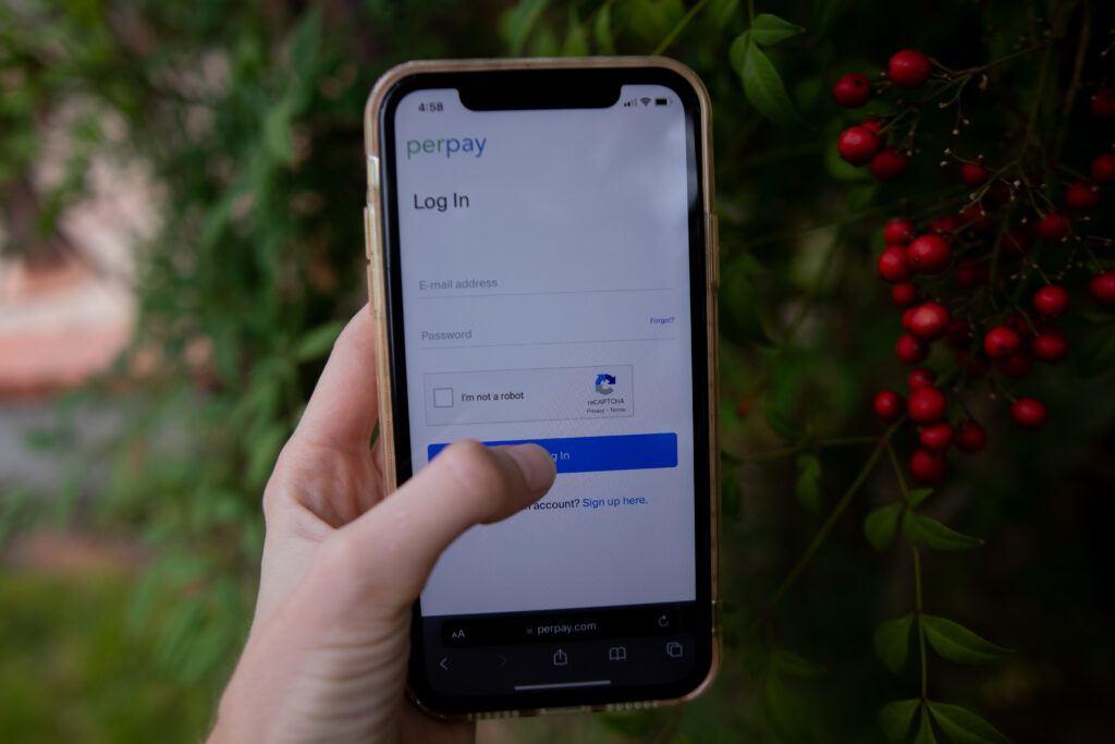 Woman's hand holding a phone, as she logs into the Perpay shopping app