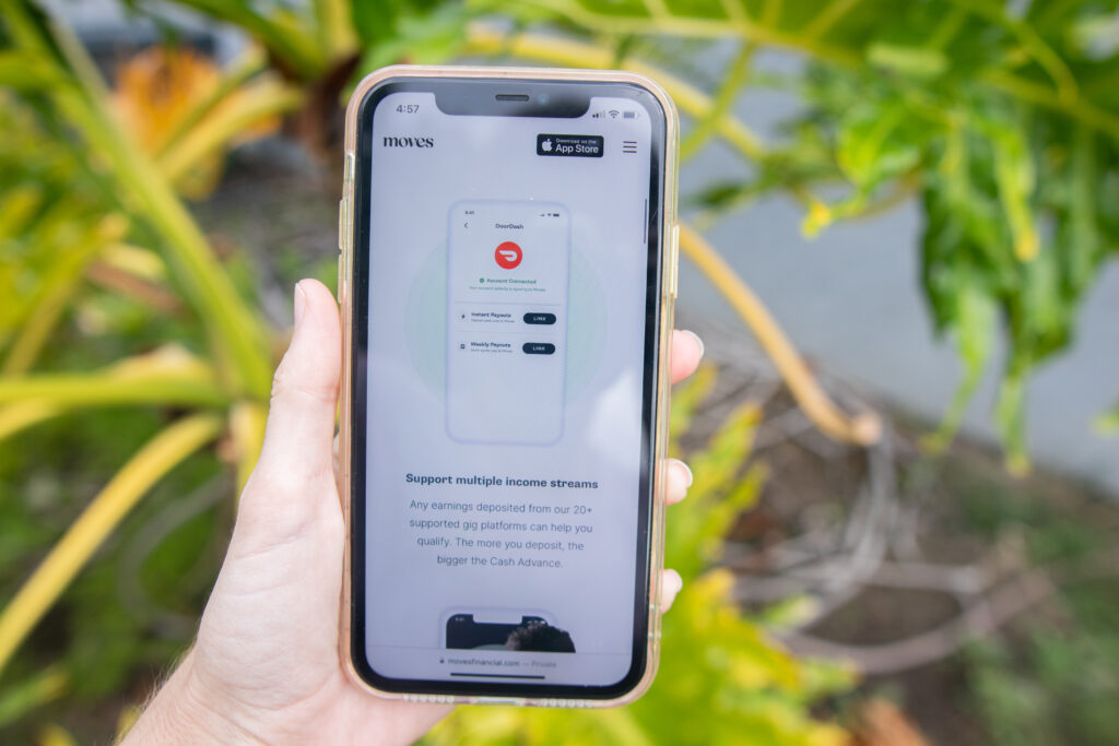 Hand holding a phone that shows Moves Financial rates and fees
