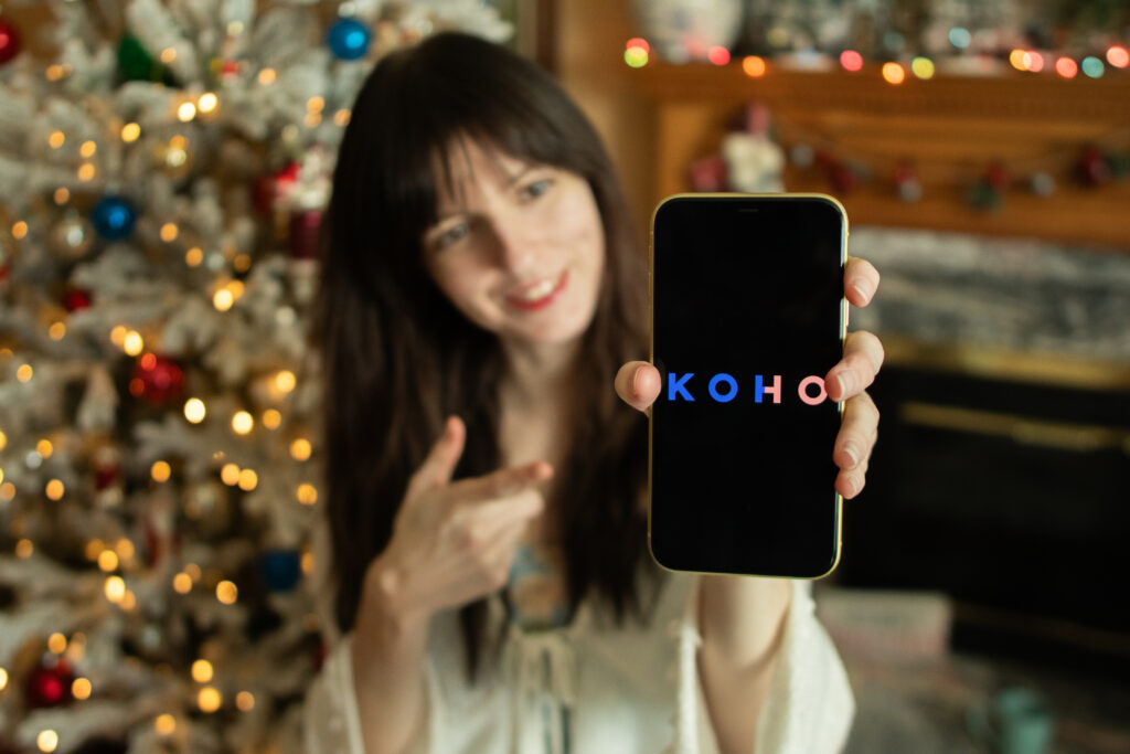 Woman holding a phone that displays the KOHO app