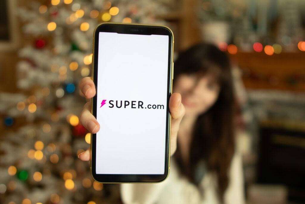 Woman holding out her phone, with the super.com app displayed on the screen