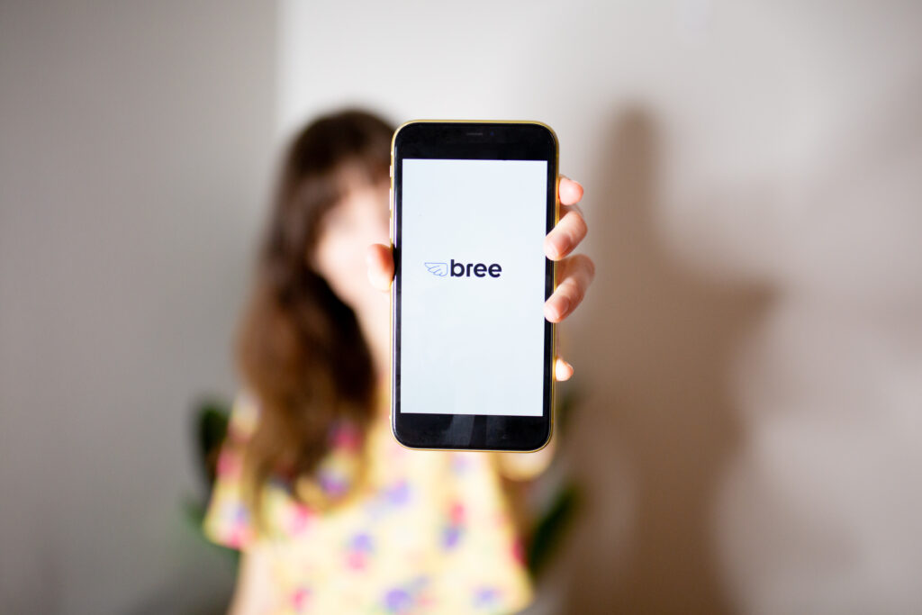 Woman holding a phone that displays the Bree loans logo